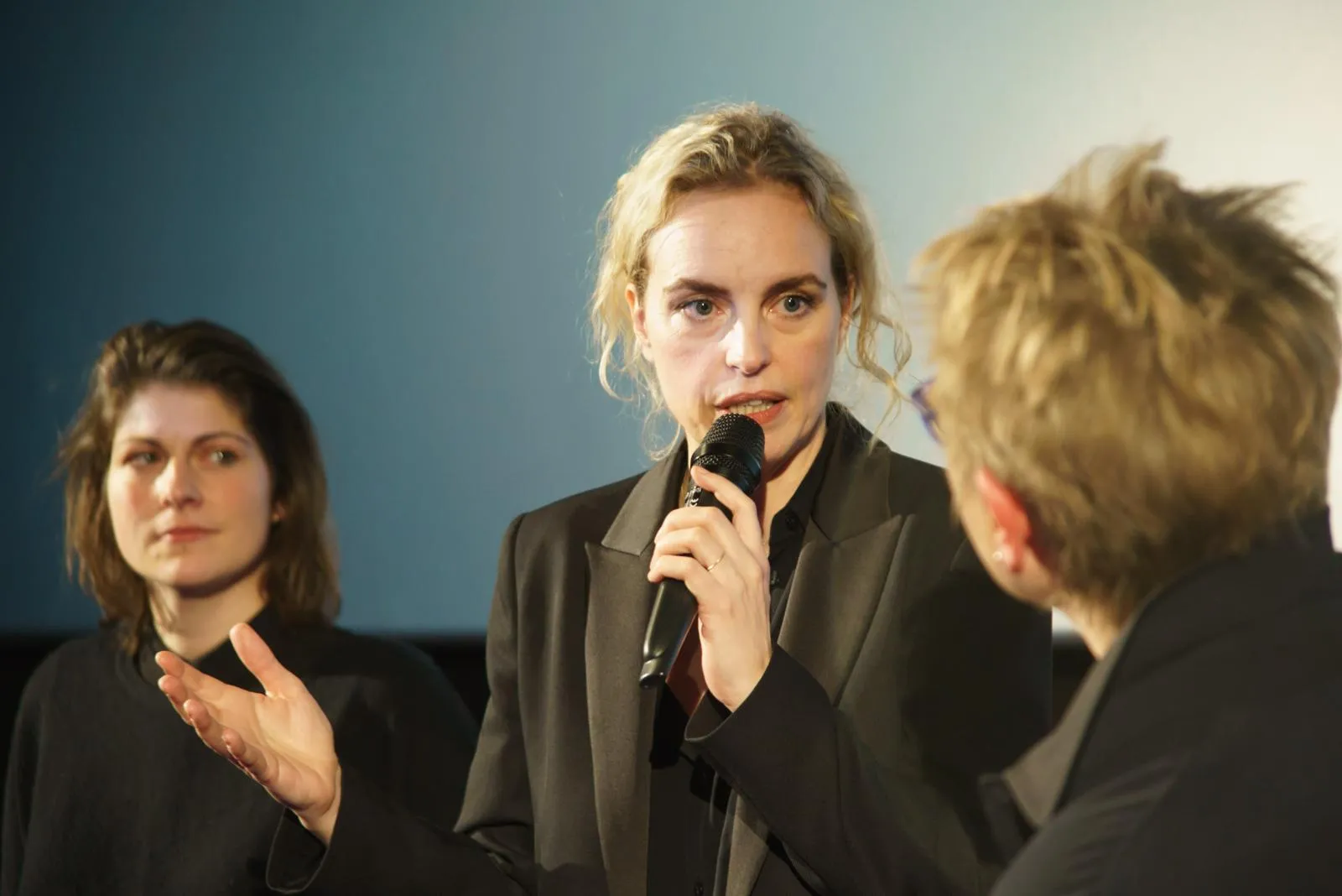 Nina Hoss spricht auf der Bühne ins Mikrofon, links eine Zuhörerin, rechts angeschnitten der Gesprächspartner.